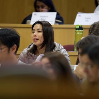 Students sitting in tiered classroom seating listen to a teaching lesson