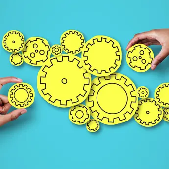 Two hands manipulating a series of cogwheels
