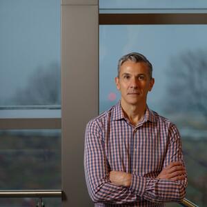 MIT Sloan Professor Emilio J. Castilla standing in front of windows in the MIT Sloan building, with wintry trees in the  background outside