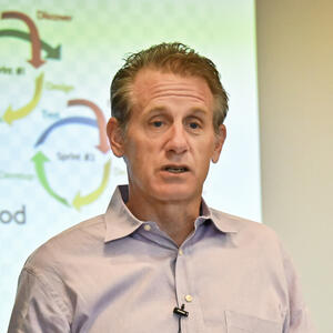 A man in a button-down shirt gives a talk