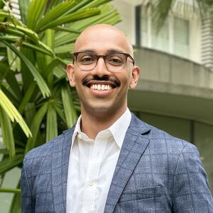 Professional photo of Shawn George with greenery in the background.