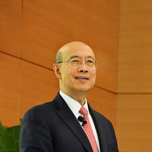 A smiling man delivers a lecture