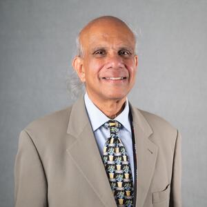 Man in tan suit poses for photo