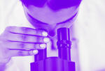 Scientist looks through a microscope