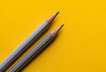 Two pencils on a mustard background