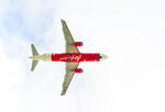 red and white air asia plane flies through a blue sky