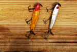 two fishing lures on a wooden surface