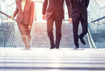 a businesswoman and two businessmen walking up a set of stairs