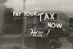 Black and white window sign that says pay your tax now here