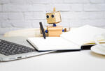 Robot writing and looking at laptop