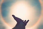Silhouette of hand against a solar flare