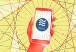 red hand holding a smartphone with Libra logo on its screen