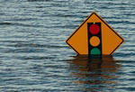 A photo of a street sign depicting an approaching stop sign. The sign is nearly underwater due to a flood.