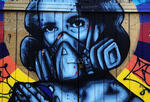 A photograph of graffiti depicting a person wearing a facemask to protect themselves against contaminants in the air.