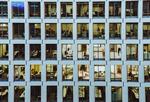 Photo of outside of a high-rise building with people working inside.