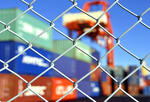 Photo of a container yard behind a chainlink fence to illustrate supply chain disruption.