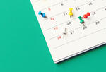 a wall calendar with colorful pins in it, meant to represent earnings timing