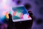 Hand holding a smartphone with lots of colors coming off the screen.
