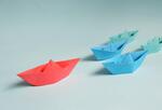 Paper origami boats on light blue background
