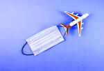 Image of airplane with a face mask trailing behind.