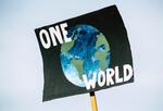 Photo of a poster with "One World" written on it and an image of the planet.