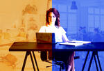 woman at desk with laptop, notebook and pen