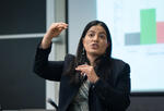 Professor Tavneet Suri teaching a class in front of a bar graph